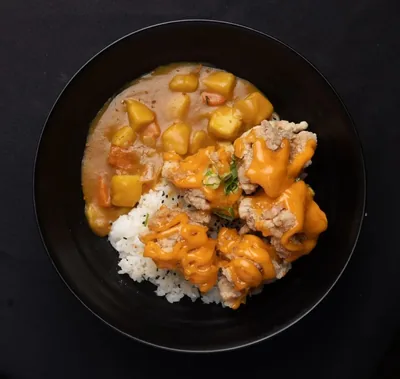 Chicken karaage curry with rice in a black bowl.