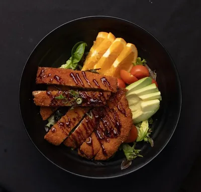 Chicken katsu salad with avocado and fresh greens.