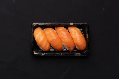 A box of fresh salmon nigiri sushi.