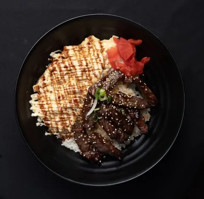 Wagyu beef donburi with rice and egg in a black bowl.